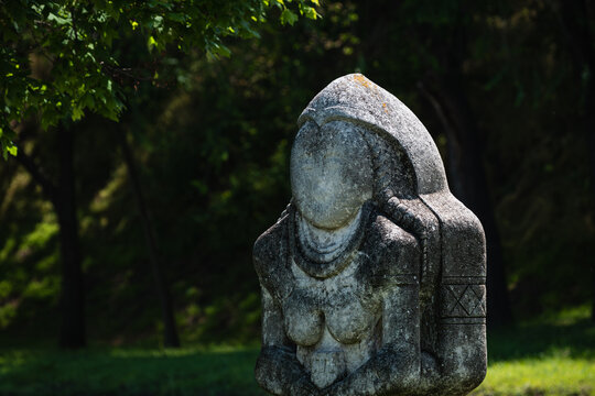 Ancient stone statue kurgan stelae standing in a green summer park