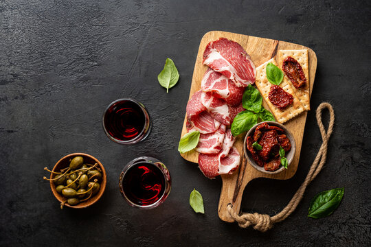 Appetizers with differents antipasti, charcuterie, snacks and red wine. Sausage, ham, tapas, olives and crackers for buffet party. Top view, flat lay