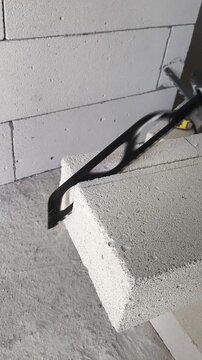 Slow motion close-up of an electric reciprocating saw cutting an aerated concrete block with a specialized masonry blade during construction work.