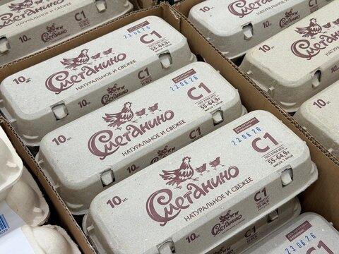 Khimki, Russia - June 25, 2026: Cardboard egg cartons featuring Russian text and a chicken logo are stacked neatly in a grocery store display