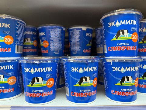 Khimki, Russia - June 25, 2026: Ekamilk sour cream containers featuring blue labels and cow graphics are neatly arranged on a supermarket shelf