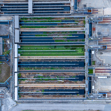 Aerial view of a water treatment plant with rectangular sedimentation tanks, filtration channels, and industrial infrastructure in Settimo Torinese, Piedmont, Italy.