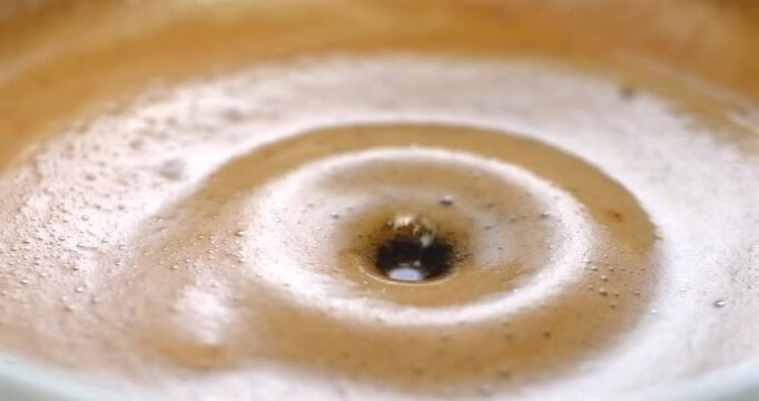 Espresso coffee drop creating a splash and ripple in crema super slow motion