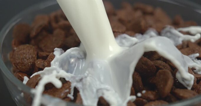 Milk pouring into bowl with chocolate corn flakes with splash in super slow motion 1000 fps