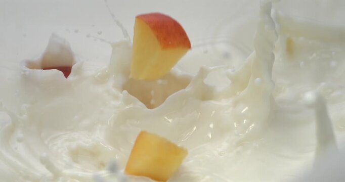 Peach slices falling into milk with splash in super slow motion 1000 fps