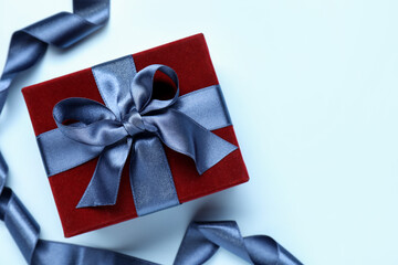 Fototapeta premium Beautiful velvet gift box and ribbon on light blue background, flat lay. Space for text