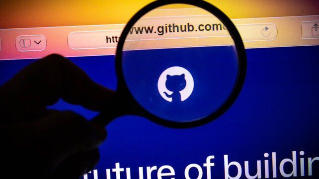Closeup of a magnifying glass held over the github logo on a computer screen