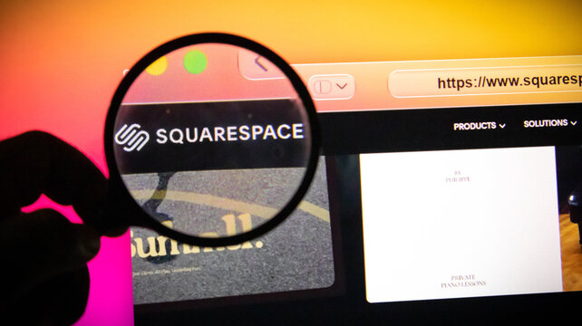 Closeup of a magnifying glass held over a computer screen displaying the squarespace website logo