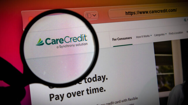 Closeup of a magnifying glass over the carecredit website logo on a screen