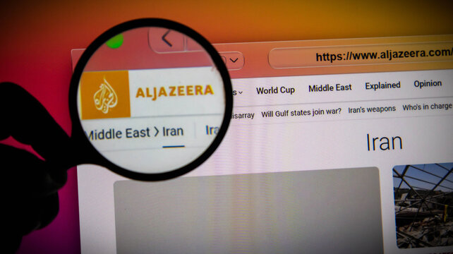 Closeup of a magnifying glass over the al jazeera news website on a screen