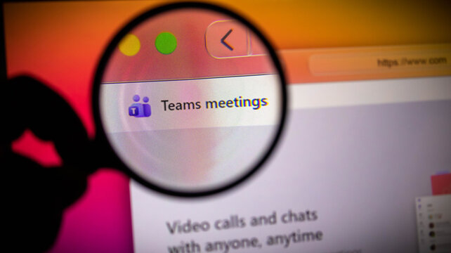 Closeup of a magnifying glass over a computer screen showing microsoft teams meetings