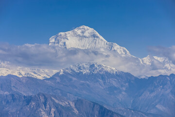 Naklejka premium Majestic view of Dhaulagiri Mountain in the Nepal Himalayas, one of the world's highest peaks. The snow-covered summit rises above rugged ridges, deep valleys, and dramatic alpine landscapes, creating