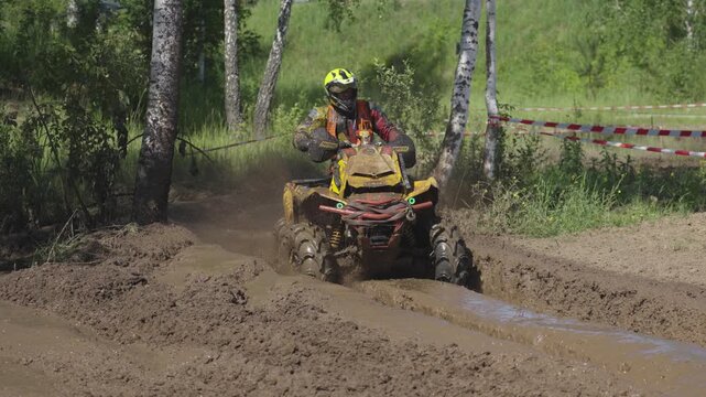 Yellow ATV racing through muddy trail with dynamic off-road action