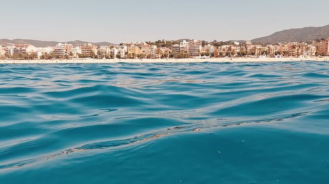 Olas del Mediterr&aacute;neo frente a la costa de El Masnou. V&iacute;deo 4K grabado desde el mar, con olas suaves en primer plano y la costa de El Masnou al fondo. Imagen tranquila de paisaje mediterr&aacute;neo, litoral