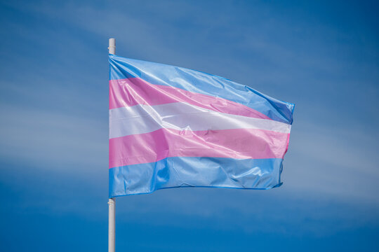 Trans flag colors and transgender pride flag wave above Lisbon, Portugal for an LGBT equality celebration, photographed in a simple outdoor scene