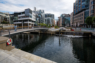 Fototapeta premium Aker Brygge Waterfront, Oslo: Modern Architecture and Pedestrian Bridge