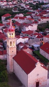 Close-up view of a historic church bell tower in Sutivan on Brač island during sunset, warm golden light illuminating stone architecture and creating a peaceful Mediterranean atmosphere.