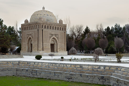 Ismail Samani Mausoleum in Bukhara with its intricate brickwork dome surrounded by a winter park. Historic Samanid dynasty tomb ideal for travel publications and heritage content.