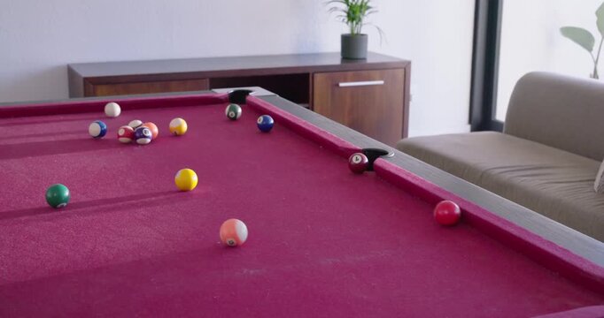 Female walking to red-felt pool table after break, inspecting balls and raising cue stick, shooting
