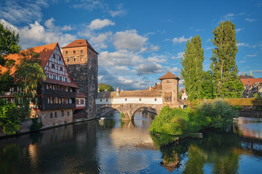 Golden sunset light illuminating the Henkersteg bridge and historical buildings on the Pegnitz river in Nuremberg, Bavaria, Germany.