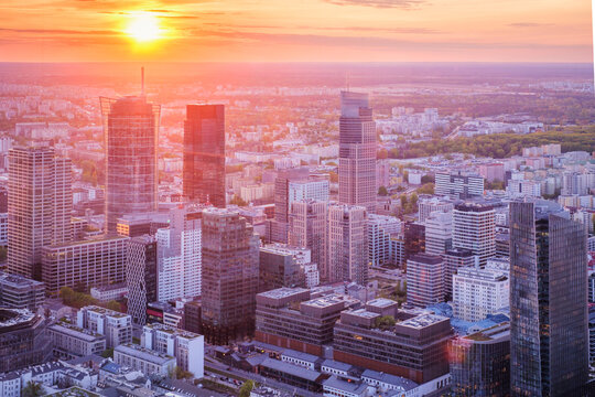 Broad view across the Warsaw skyline in Poland with skyscrapers, cityscape layers, shadowed buildings, sunset color and dramatic sky