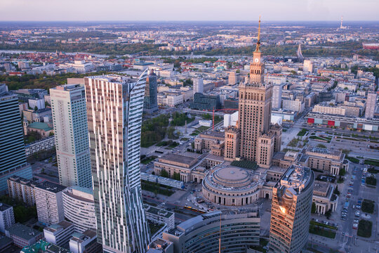 Broad view across Warsaw, Poland, with the Palace of Culture landmark, skyline towers, historic tower, sunset color and dramatic sky