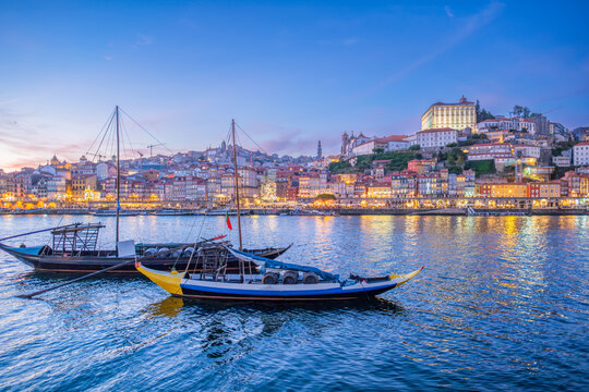 Night view of Porto rabelo boats on Douro River by Ribeira, Portugal, with evening twilight, blue hour lights and moored boats along Vila Nova de Gaia, calm water