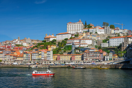 Tourist boat crosses the Douro River in Porto, Portugal, below Ribeira riverfront and the historic hillside cityscape