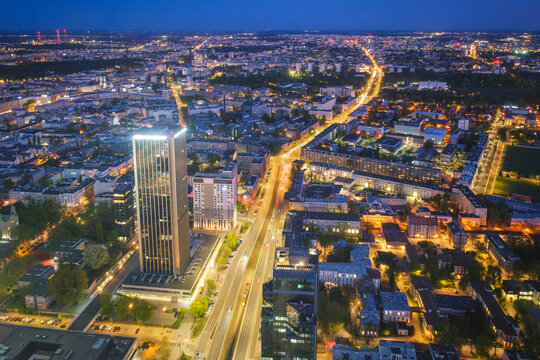 Broad view across the Warsaw skyline in Poland with skyscrapers, city lights, nightfall color, blue hour twilight and evening glow