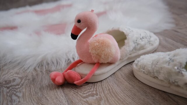 Warm and inviting children&rsquo;s room, soft white winter slippers with a snowflake pattern. Fluffy rug and cute stuffed flamingo toy adds a playful pop of color and charm. Comfort and magic of winter. 
