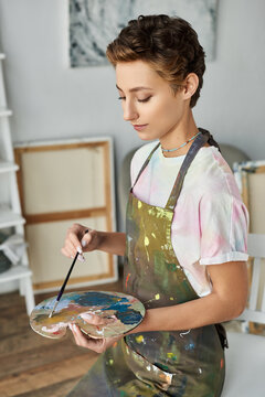 Inside her cozy home, a young woman expresses her creativity by painting a vibrant picture with passion.