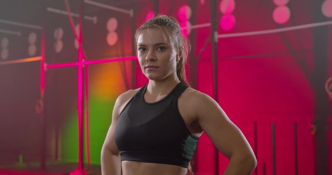 Female athlete wearing sports bra posing while camera closing in on rig, softening smile for ad