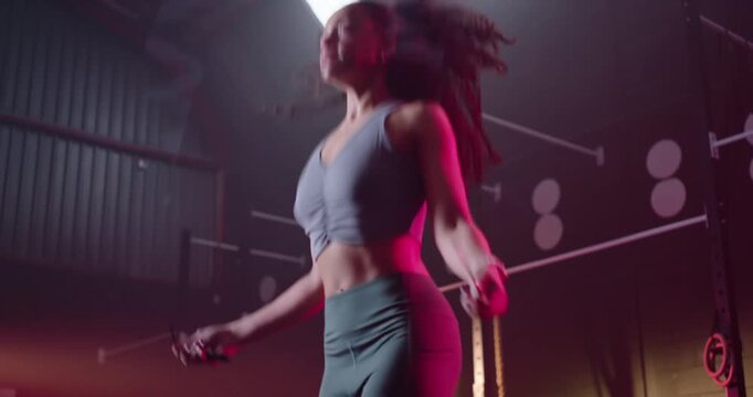 African American woman starting warmup for cardio, jumping rope in studio in crop top and leggings