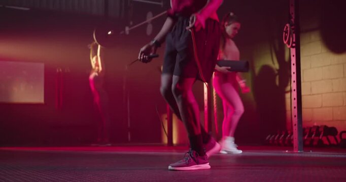 Diverse gym partners African American man skipping rope, warming up for training with step platform
