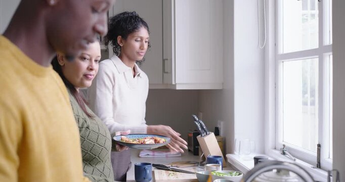 African American man rinsing colander in sink after hands comparing carrots, friends prepping meal