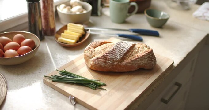 Camera is pushing in and focusing on loaf of crusty bread on cutting board for plating