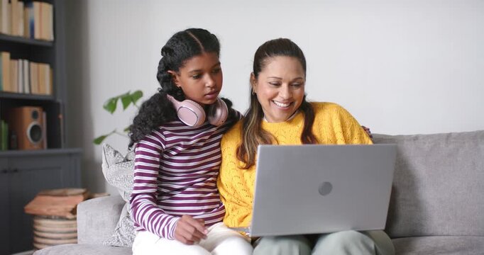 African-American mom and teen daughter leaning at home pointing at laptop after seeing pic hugging