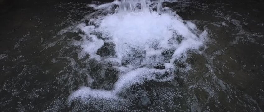 Horizontal cinematic 4K 120fps slow motion video of water falling close up. Abstract widescreen texture of bubbling liquid stream splashing with white foam and rushing waves in a pool background