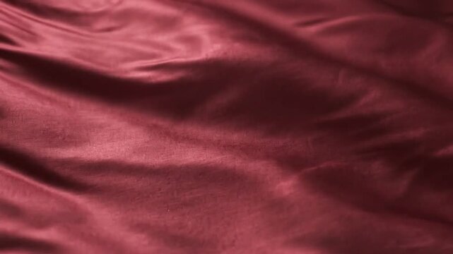Deep red satin fabric with folds and soft highlights creating a and smooth textured background surface Keywords: red, satin, fabric, silk, texture, background, smooth, soft, folds, drapes, flowing