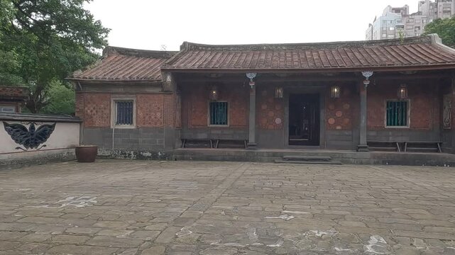 Horizontal 4K 60fps video of Lin An Tai Historical House in Taipei. Pan right camera movement from the traditional moongate door across the courtyard to the historic Chinese family residence