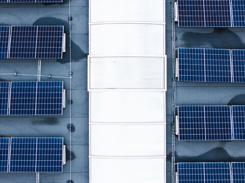 Aerial view of solar panels installed on the roof of a cheese factory with a central skylight in Ikskile, Ogre Municipality, Latvia.