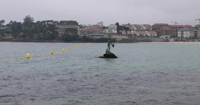 Bronze sculpture of madama de silgar standing on rocks in the water near the beach