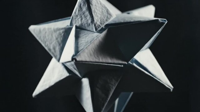 Abstract origami star decoration gracefully suspended against a stark black backdrop, creating a captivating visual