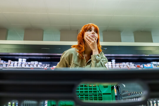 Woman experiencing concern over rising food prices in supermarket