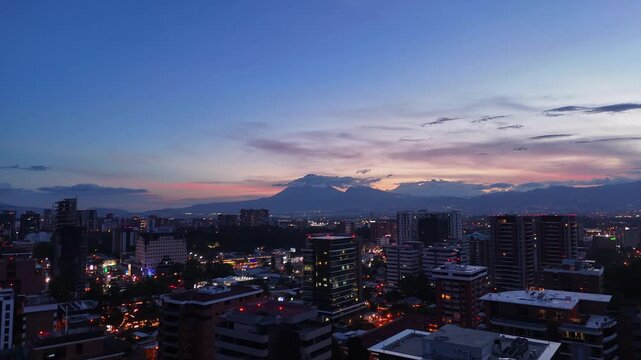 Vista de altura de Ciudad de Guatemala con rascacielos residenciales y luces urbanas de noche. Atardecer dram&aacute;tico y colorido sobre el horizonte de la Ciudad de Guatemala.