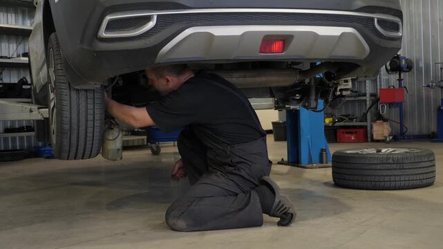 The mechanic repaired the car at the service station. He drained the brake fluid and checked under the car, which was on the lift.