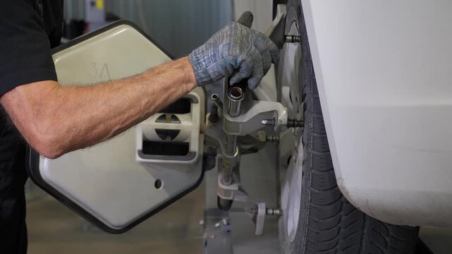 Installation of wheel balancing equipment at a modern service station: A locksmith tightens bolts on the wheel. Wheel balancing and wheel alignment.