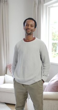 Vertical video: African American man shifting weight tilting head then smiling laughing at home