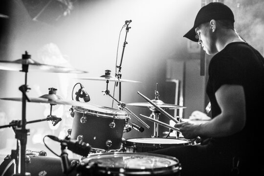 Drummer performing live on stage in black and white