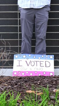 Man holding a humorous, satirical campaign sign reading I Voted for a nap, capturing themes of election fatigue, voting fatigue, and political burnout
